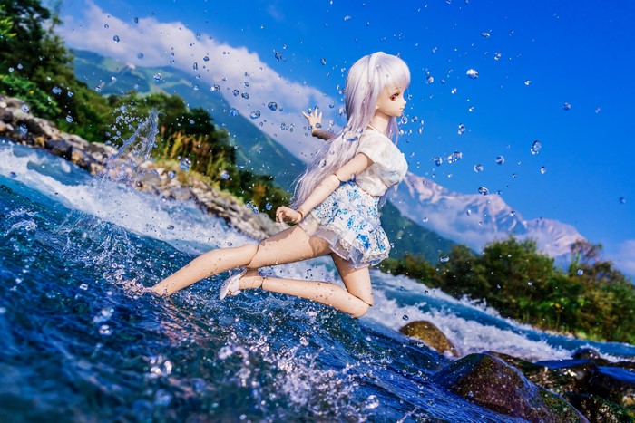 Doll running through water with mountains in background