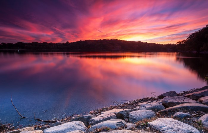 Lake with colorful sunset reflection and rocky shore