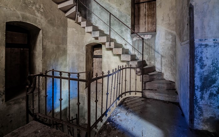 Abandoned stone staircase with metal railing