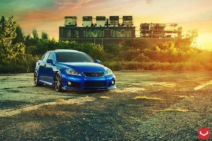 Blue Lexus IS parked in front of an industrial building