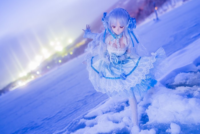 Doll in a blue dress on snow