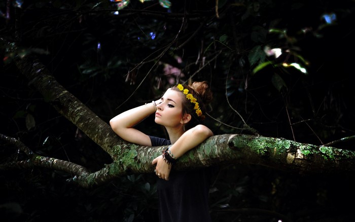 Girl with flower crown on tree branch