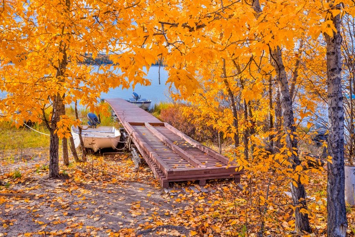 Autumn scene with boats and a wooden dock on a lake