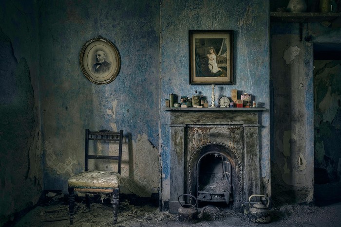 Abandoned room with fireplace and portraits