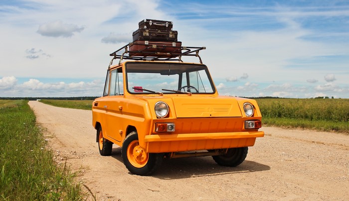 Orange SMZ cycle-car with suitcases on a dirt road