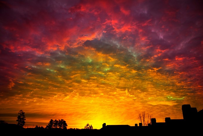 Dramatic sunset with colorful clouds over silhouetted rooftops