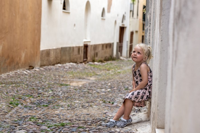 Young girl sitting on a cobblestone street