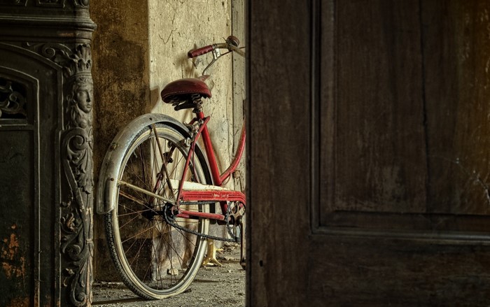 Red bicycle leaning against a wall