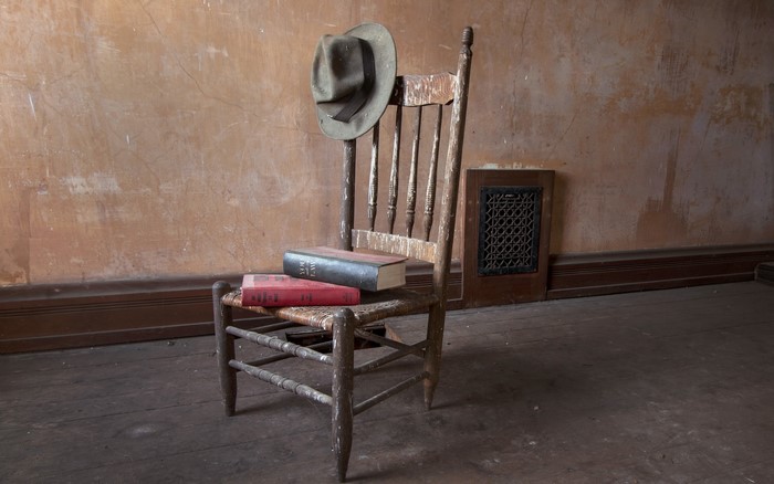 Old wooden chair with books and hat