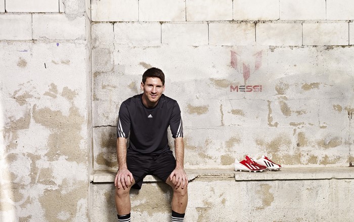 Lionel Messi sitting on a bench with soccer cleats