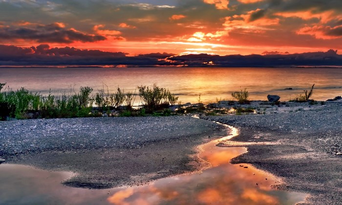 Sunset over a rocky lake shore with reflections