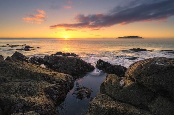 Sunrise over the sea with rocks and island