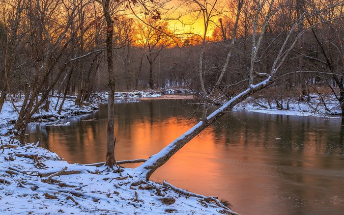 Winter river at sunset with snow-covered trees