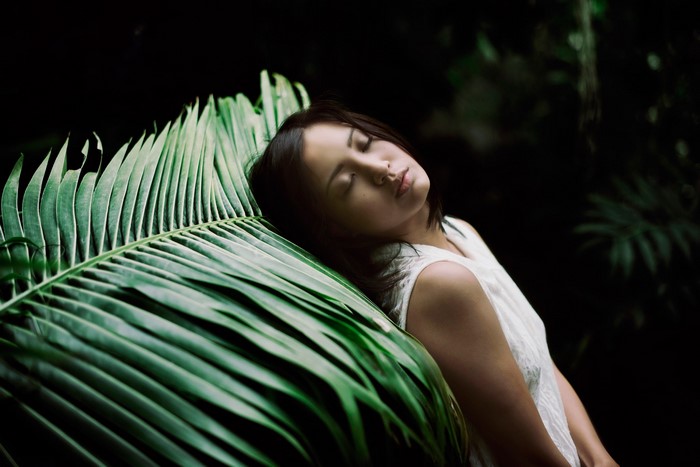 Asian woman sleeping on a large green leaf