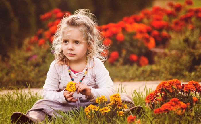 Young girl sitting in grass with flowers