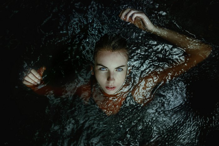 Woman with blue eyes in dark water
