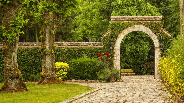 Stone Archway Entrance to a Garden with Trees and Flowers