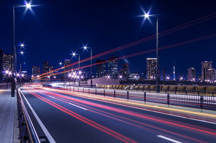 Tokyo cityscape at night with light trails on a bridge