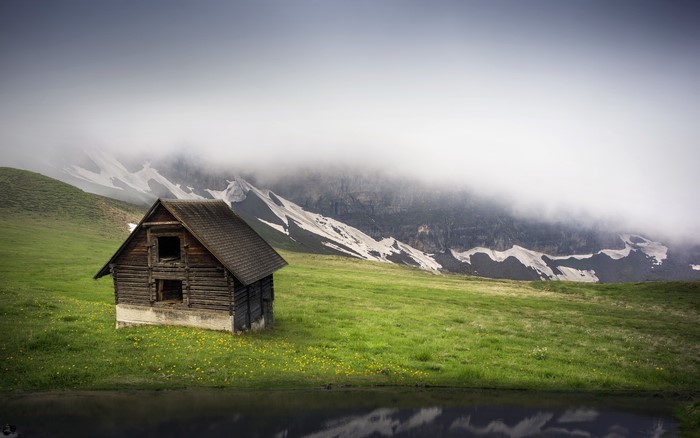 Wooden cabin in foggy mountains with a lake