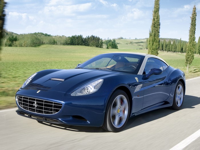 Blue Ferrari California driving on a road