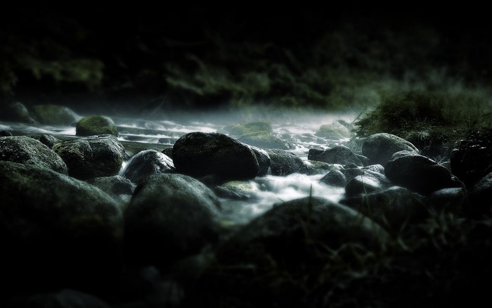 River flowing over stones in dark forest