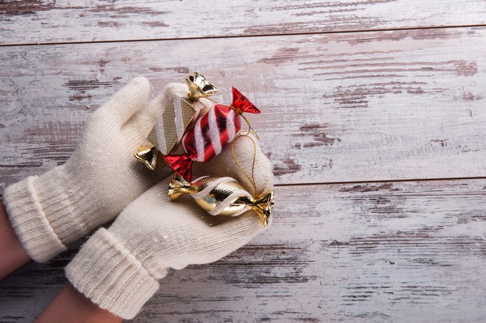 Hands in Gloves Holding Christmas Candy Ornaments