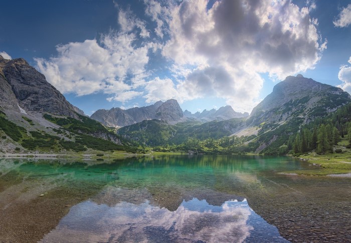Turquoise mountain lake with reflection and clouds