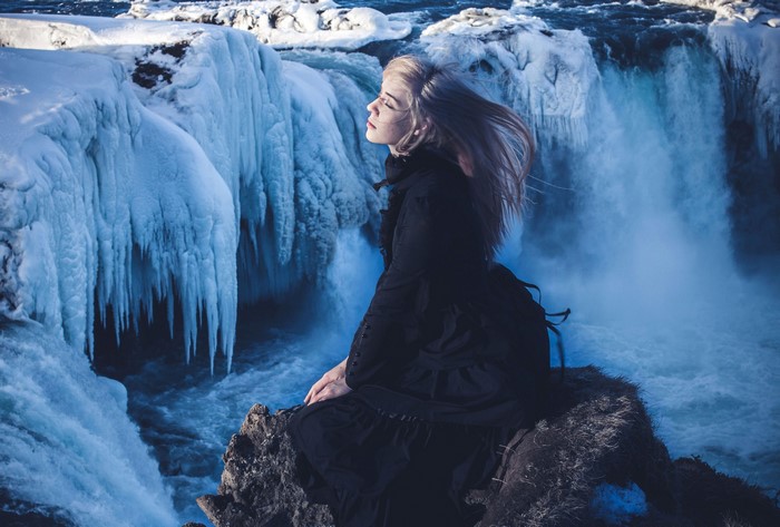 Woman in black dress at Godafoss waterfall in Iceland
