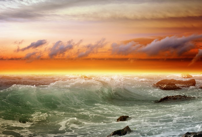 Ocean waves crashing on rocks at sunset