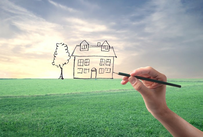 Hand drawing a house and tree in a field