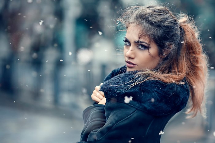 Woman in winter coat with snow falling