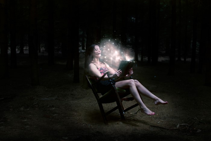 Woman reading a magical book in a dark forest