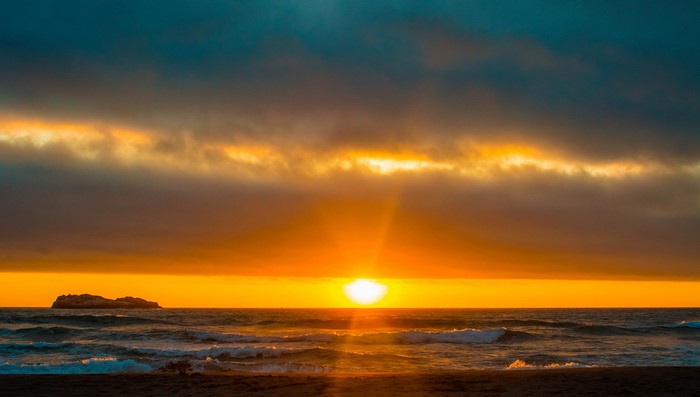 Sunset over the ocean with a small island