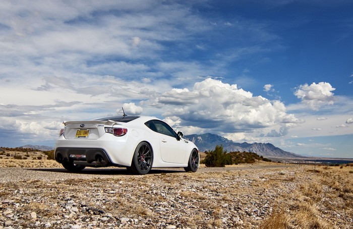 White Subaru BRZ parked on a rocky road with mountains in the background