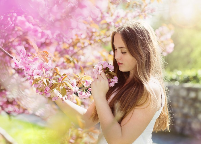 Girl smelling pink cherry blossoms