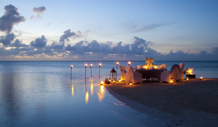 Romantic beach dinner at dusk with torches and candles