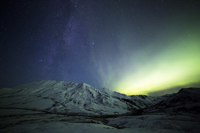 Aurora Borealis over snow-covered mountains at night