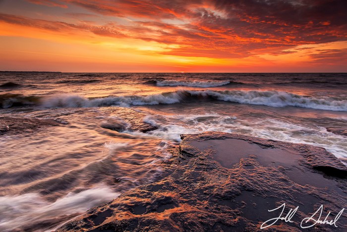 Fiery Sunset Over Ocean Waves and Rocky Shore