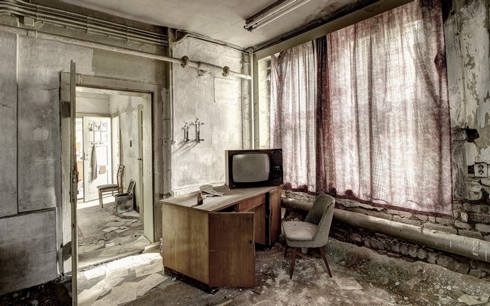 Abandoned room with old TV set and desk