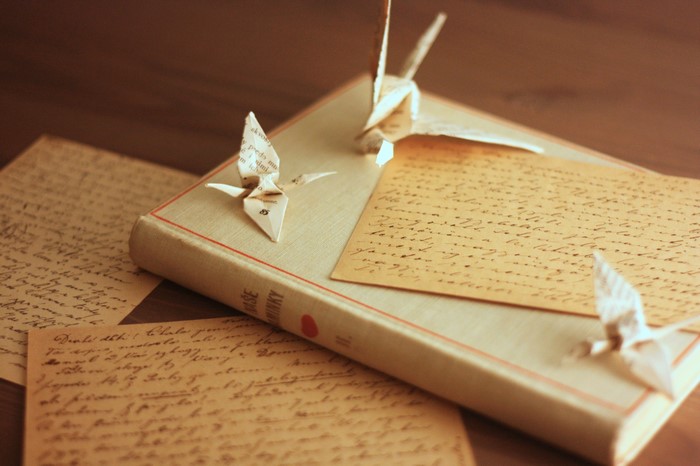 Origami cranes on a book with old letters