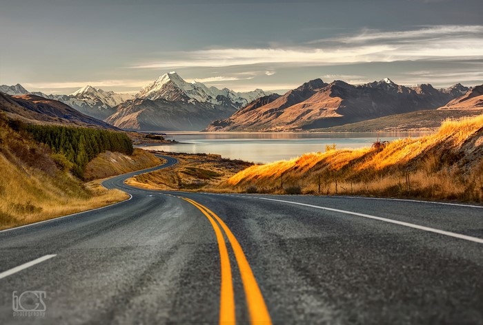 Road leading to snow-capped mountains and a lake