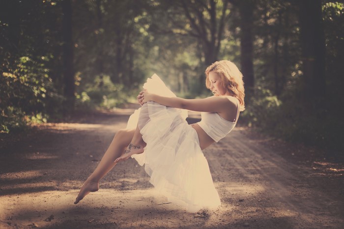 Blonde girl in white dress on a dirt road