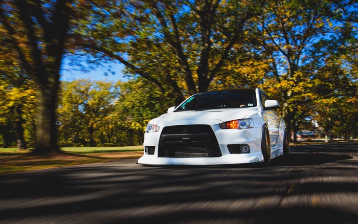 White Mitsubishi Lancer Evo X driving on a road