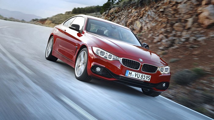 Red BMW 4 Series Coupe driving on a winding road