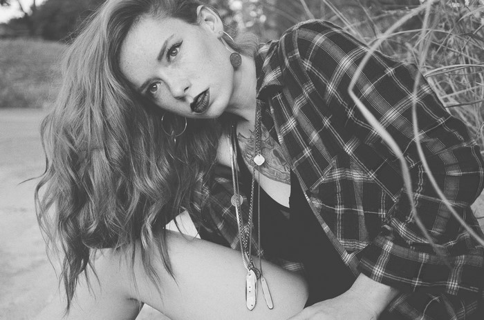 Woman with red hair wearing plaid shirt and necklaces