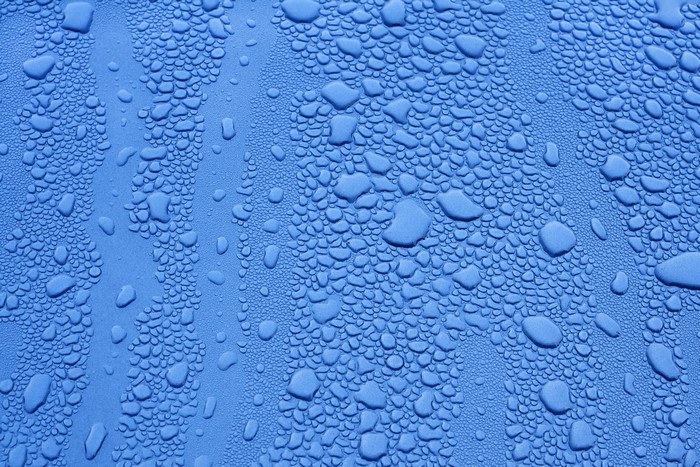 Closeup of water droplets on a blue textured surface