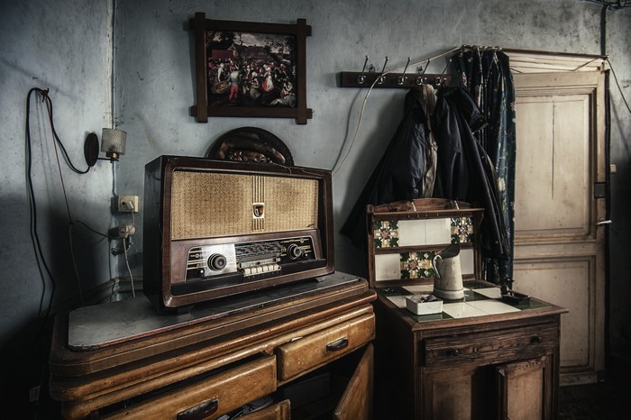 Retro radio on a wooden dresser with coats hanging
