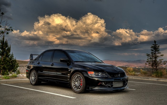 Black Mitsubishi Lancer Evolution parked under dramatic clouds