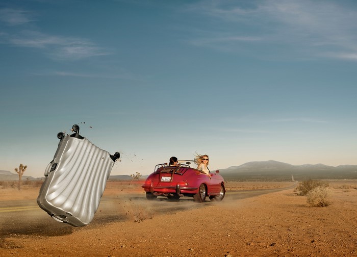 Suitcase falling from a red convertible in the desert
