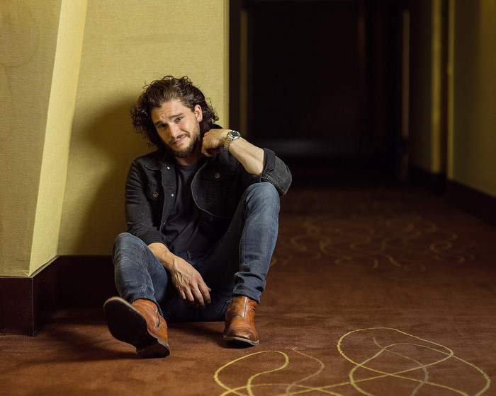 Kit Harington sitting in a hallway